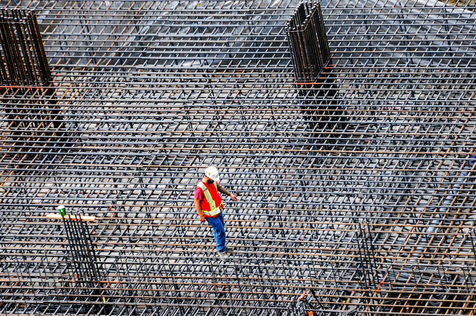 Construction worker in PPE checking reinforcing steel on site