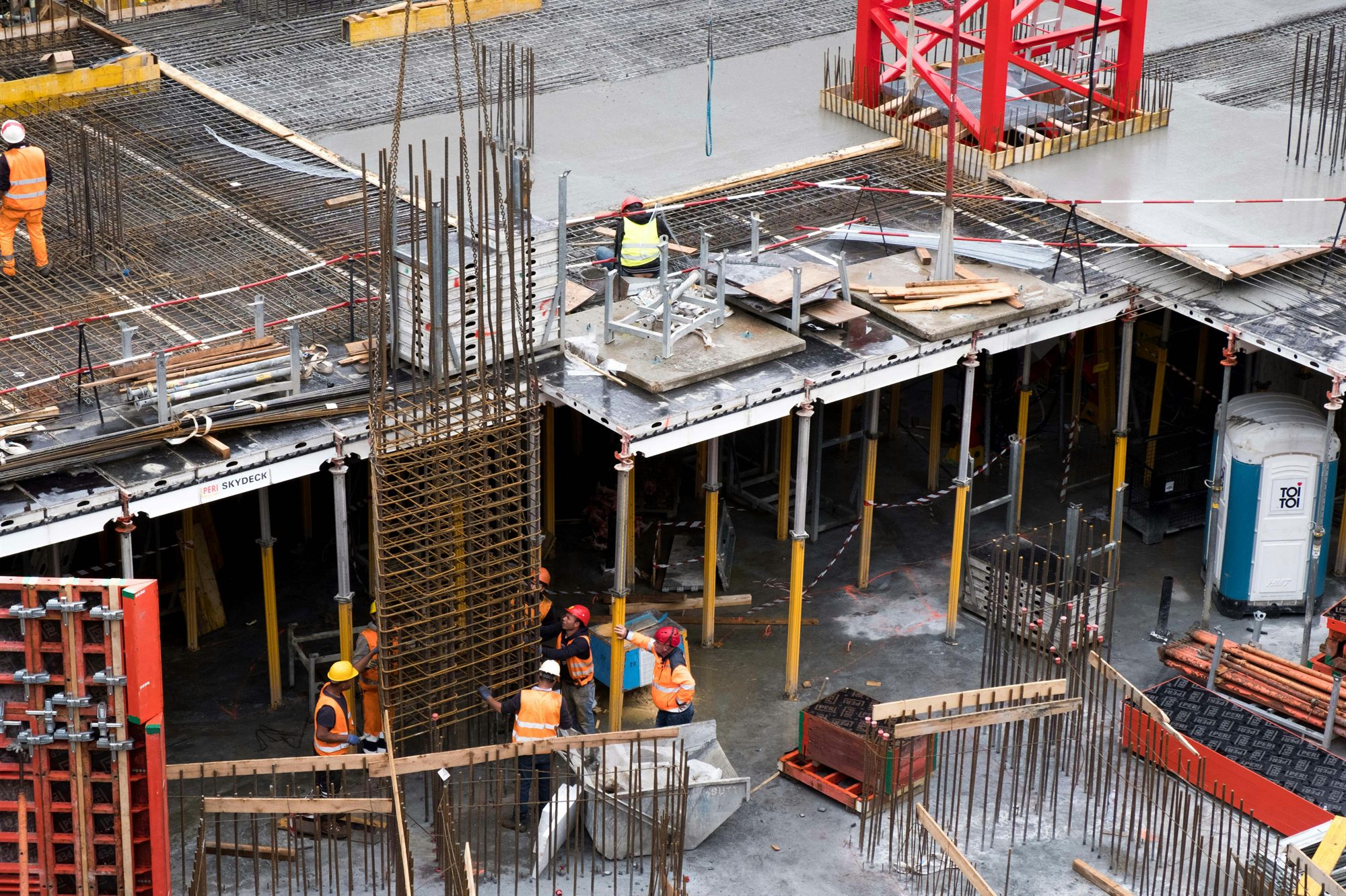 Construction workers in PPE coordinating slab work on site
